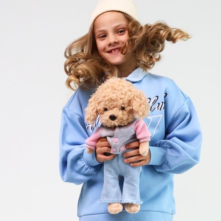 Peluche Lucky Doggy debout en veste universitaire rose et pantalon en jean clair.